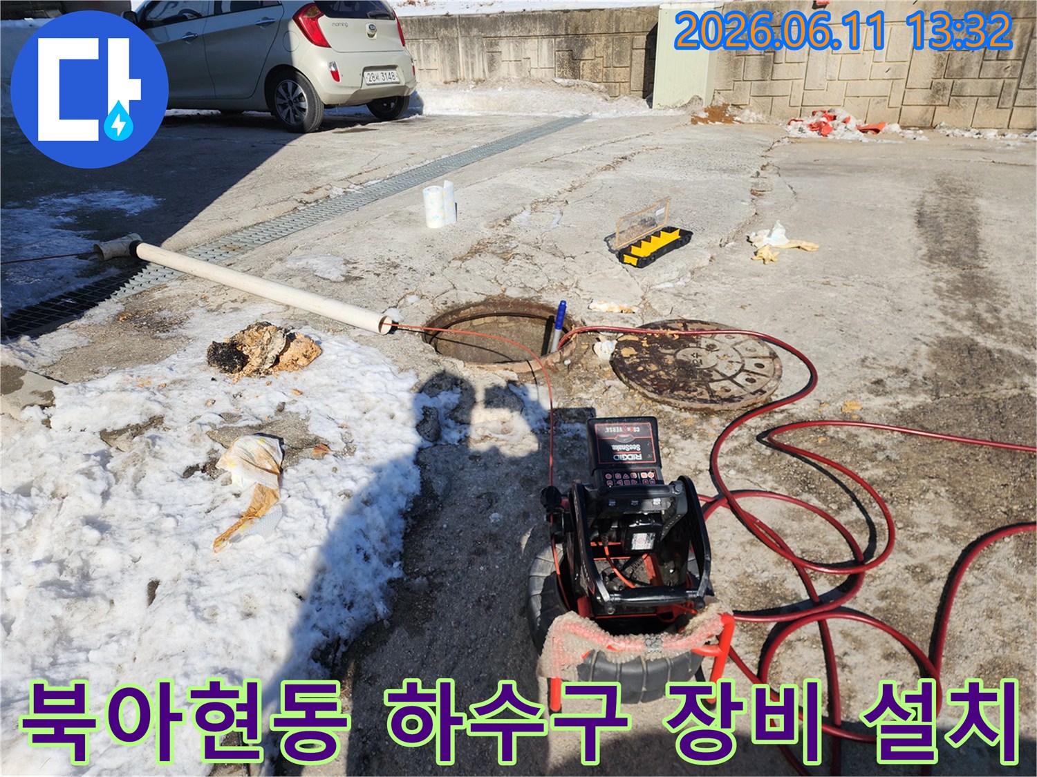야외 맨홀 근처에서 진행되는 배관 고압 세척 작업용 장비 배치 사진입니다.
