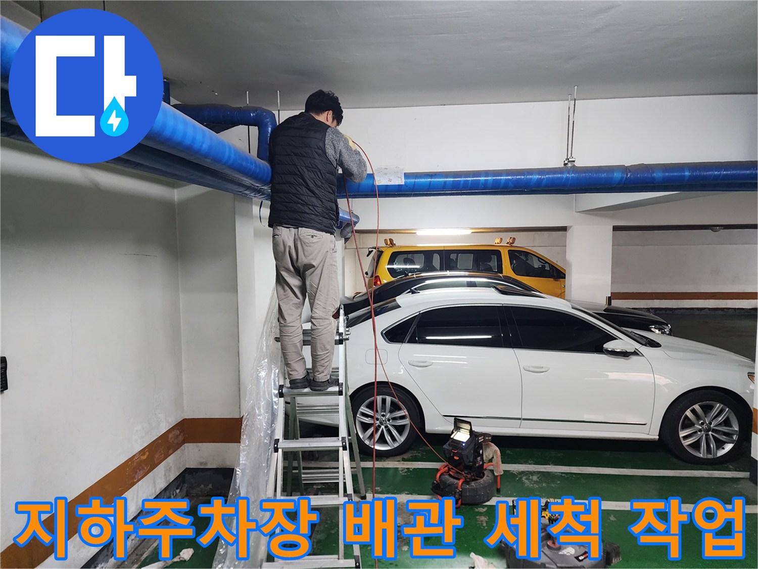 지하주차장 천장 파란색 배관에서 고압세척 작업을 진행하는 엔지니어
