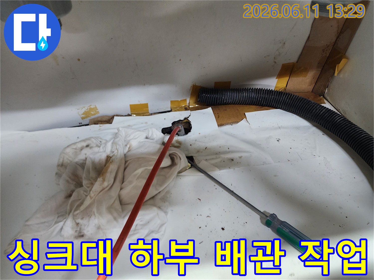 광진구 중곡동 싱크대 하부장 내부의 검은색 주름관과 배관 점검 도구가 놓여 있는 모습