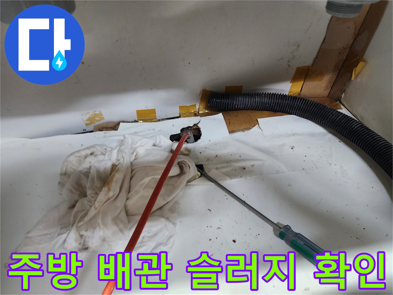 싱크대 아래쪽 검은색 주름관과 작업 도구가 놓인 현장 사진