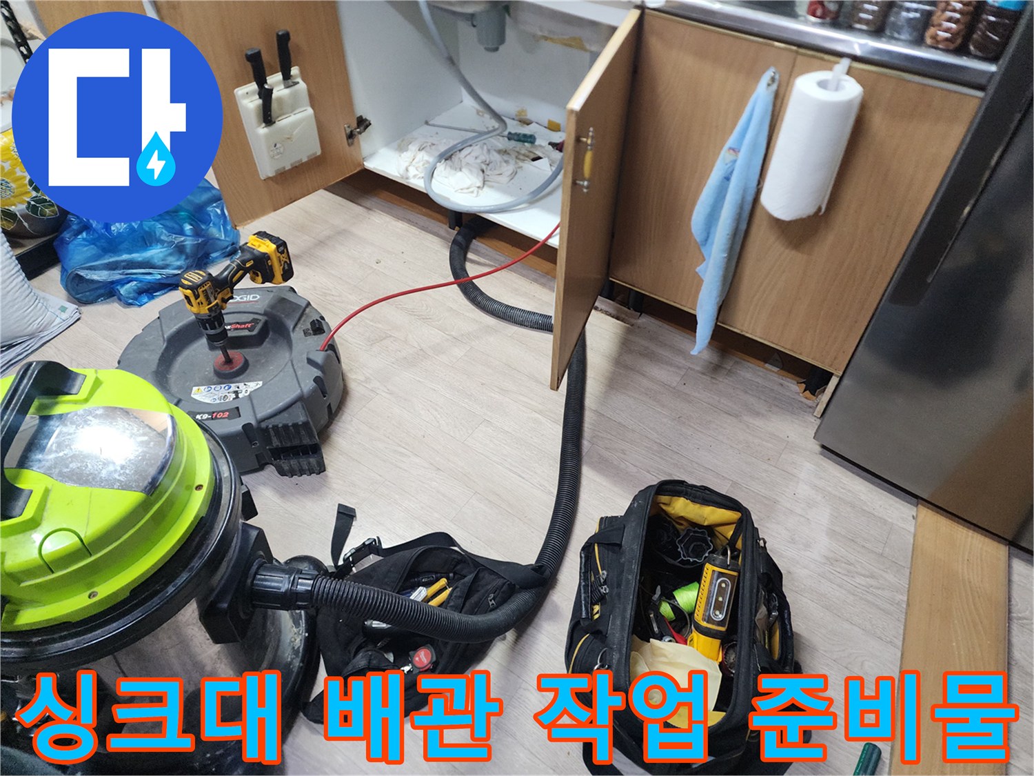 주방 싱크대 하단 배관 청소를 위해 세팅된 전문 장비와 공구함
