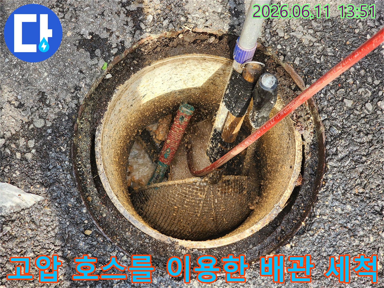 맨홀 안쪽 배관 구멍으로 투입된 고압 세척 장비와 붉은색 호스