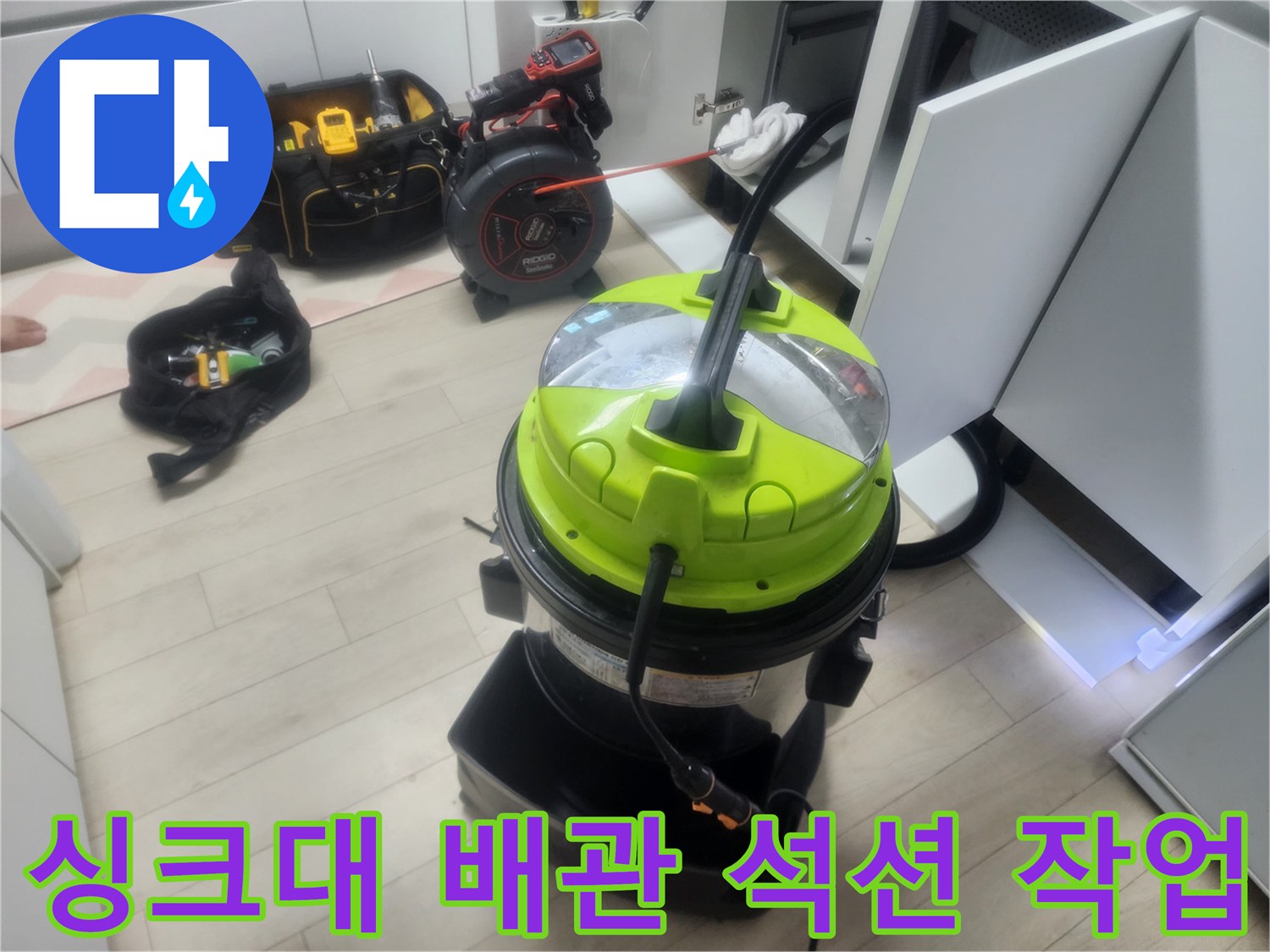 싱크대 하단 배수 배관의 막힌 부분을 뚫기 위해 석션기를 사용하는 현장입니다.