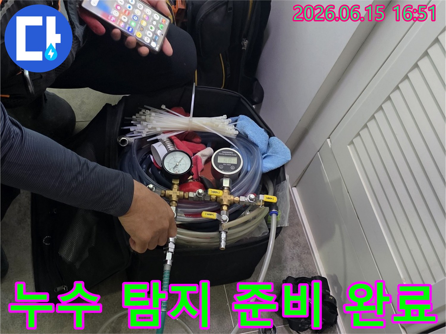 현장에서 누수 탐지 장비를-조작하며-스마트폰으로 데이터를 분석하는 엔지니어