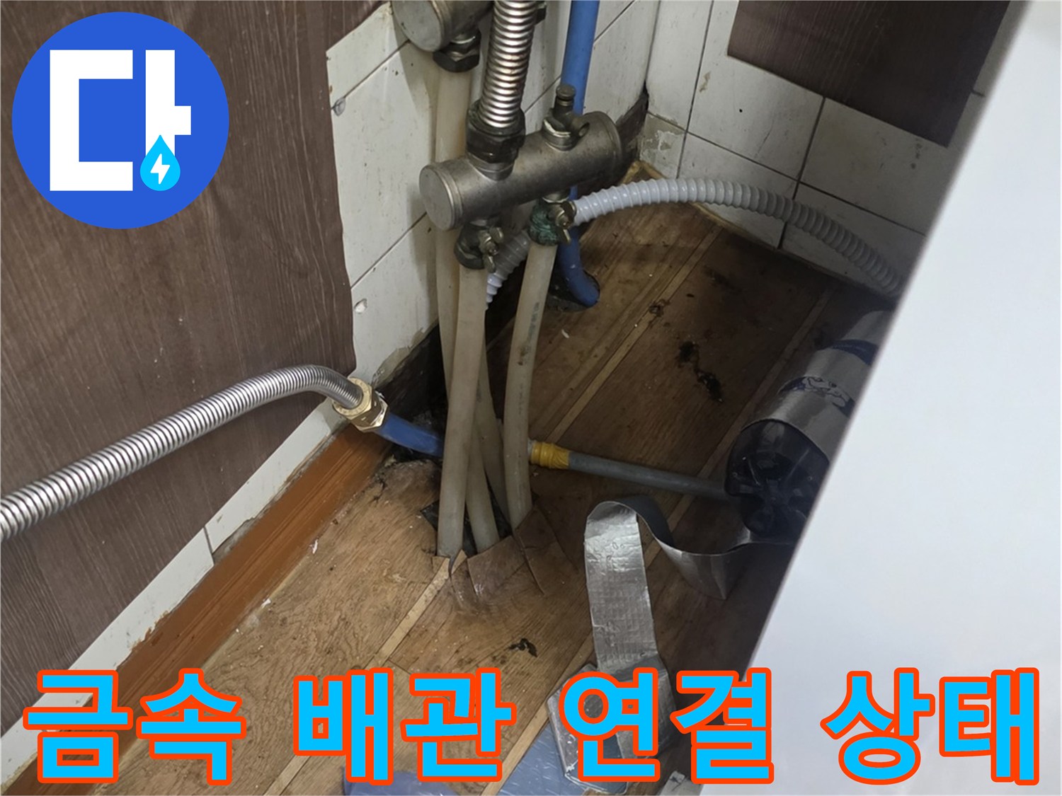 싱크대 하단 금속 주름관과 부속품들이 모여 있는 모습