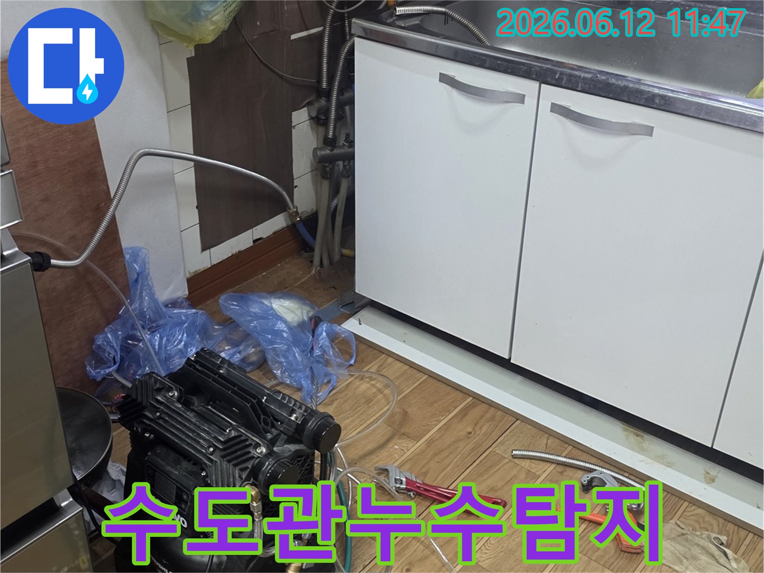 주방 싱크대 아래-수도관 누수를 탐지하기 위해-전문 장비를 연결하고-점검하는 작업 현장