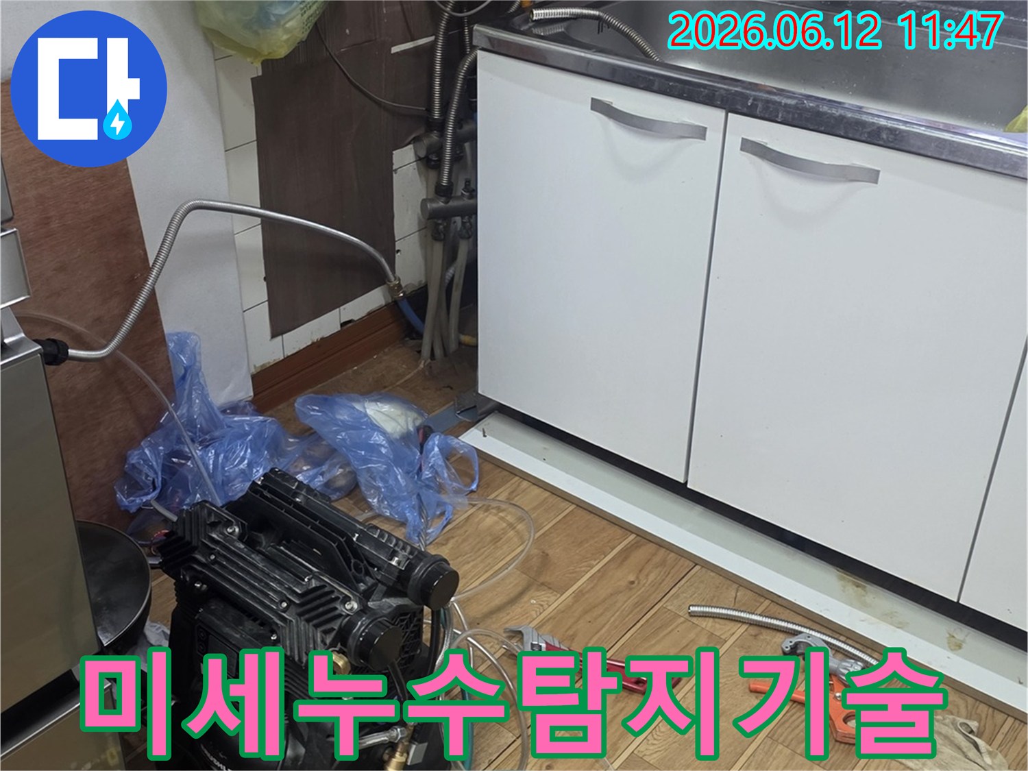 주방 싱크대 하부에서-미세 누수를 탐지하기 위해-첨단 장비를 연결하고-정밀하게 점검하는 모습