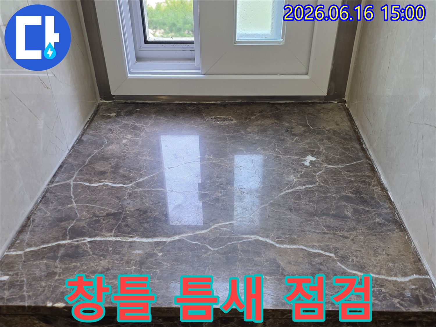 창틀과 대리석 사이의-미세한 틈새를 면밀히 점검하며-누수 발생 가능성을 확인하는 모습