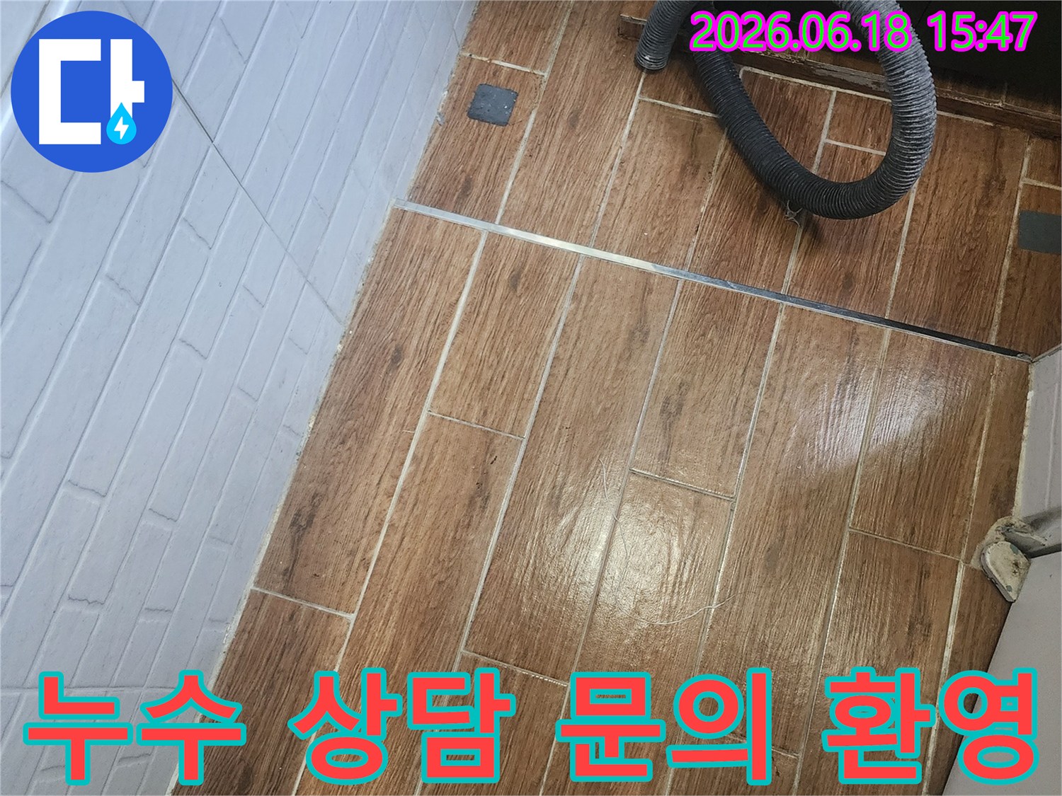염창동 아파트에서 누수 상담을 위해 언제든지 문의할 수 있도록 탐지 작업이 진행 중인 현장 사진입니다-바닥 타일 위에 검은색 호스가 놓여 있습니다.