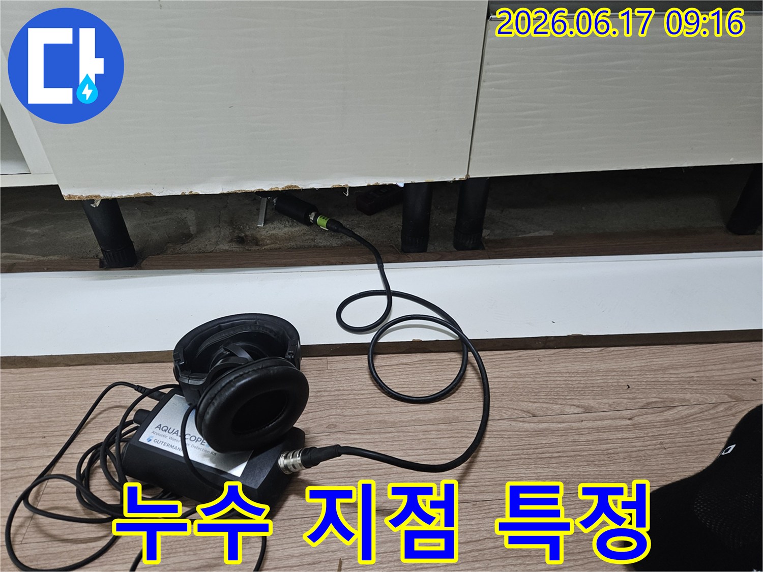 누수 탐지 엔지니어가-첨단 청음식 장비를 사용하여-싱크대 하부의 누수 지점을 특정하는 모습