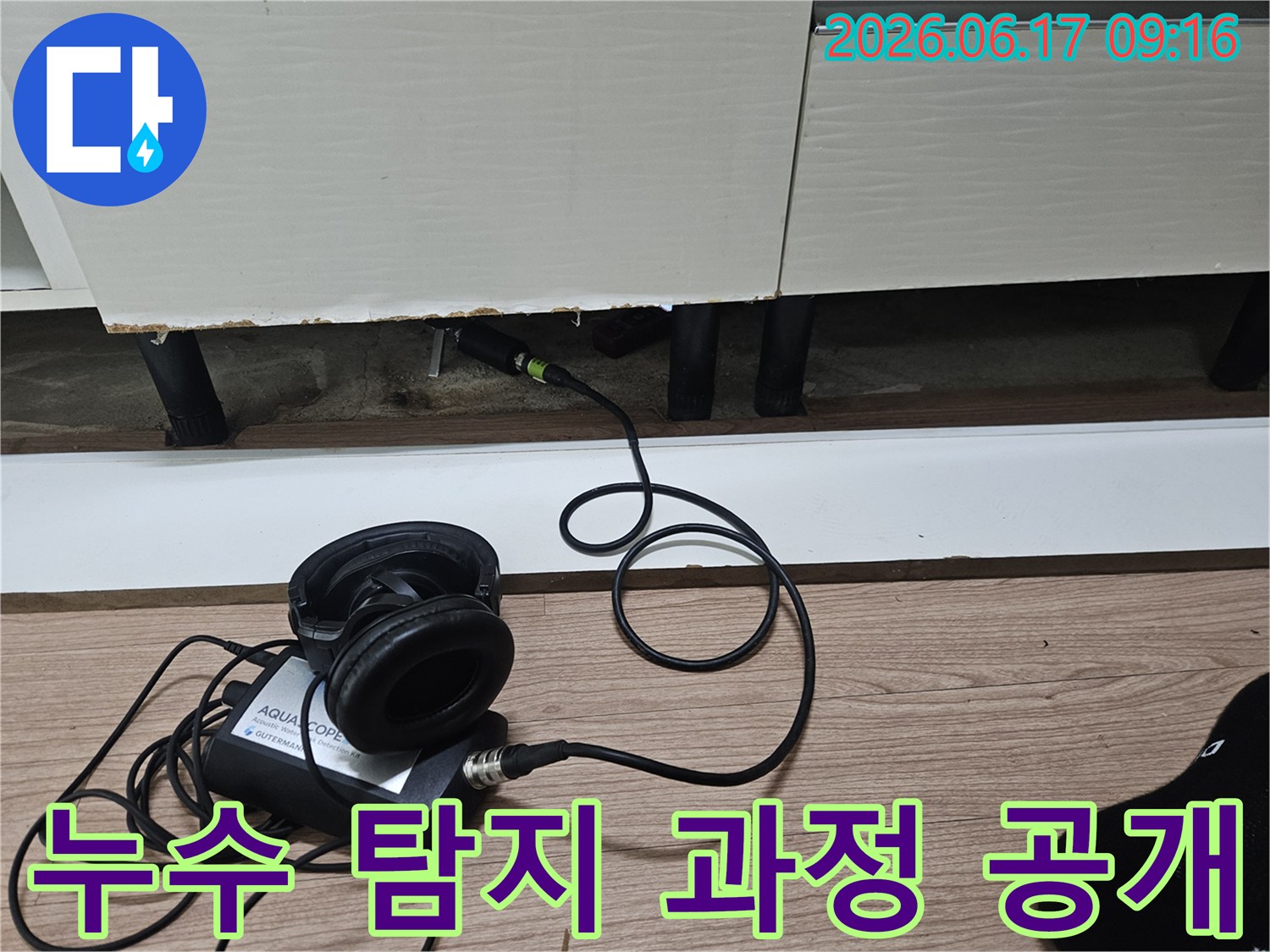 누수 탐지 엔지니어가-청음식 장비를 사용하여-싱크대 하부장 아래 누수 지점을 탐지하는 과정을 보여주는 모습