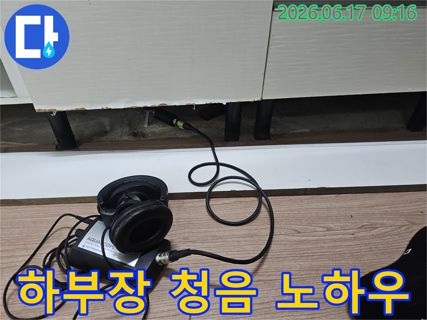 누수 탐지 엔지니어가-청음식 장비를 사용하여-싱크대 하부장 아래 누수음을 탐지하는 노하우를 보여주는 모습