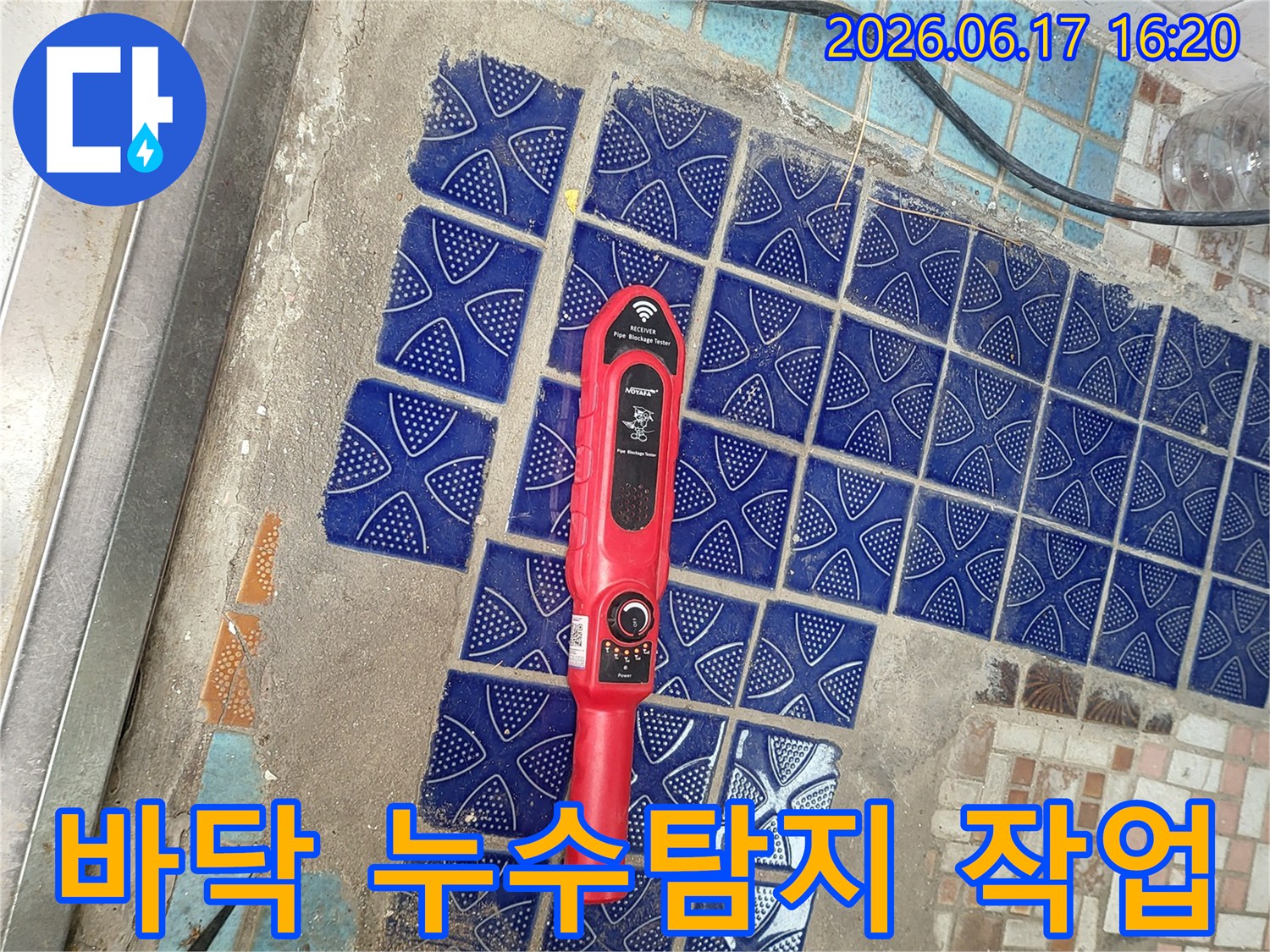 손잡이가 달린 붉은색 탐지기가 파손된 욕실 타일 위에 놓여-누수 지점을 찾는 중인 현장