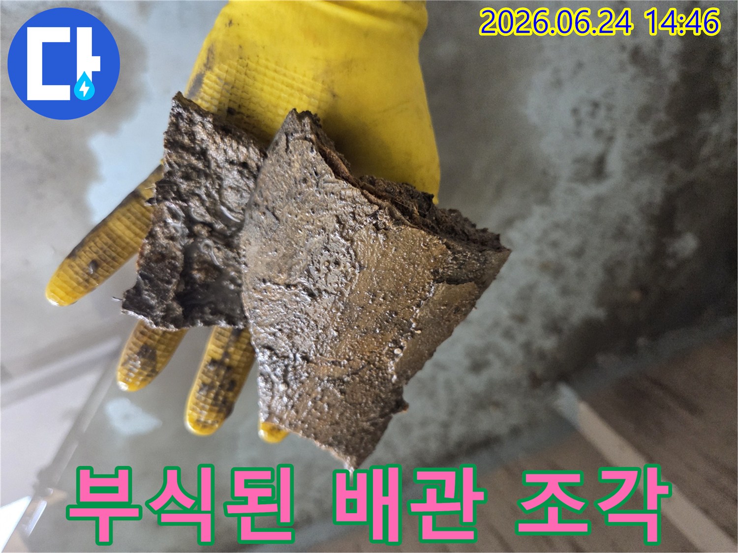 노란색-장갑을-낀-손이-오래된-수도관에서-나온-부식된-이물질-조각들을-들고-있는-모습