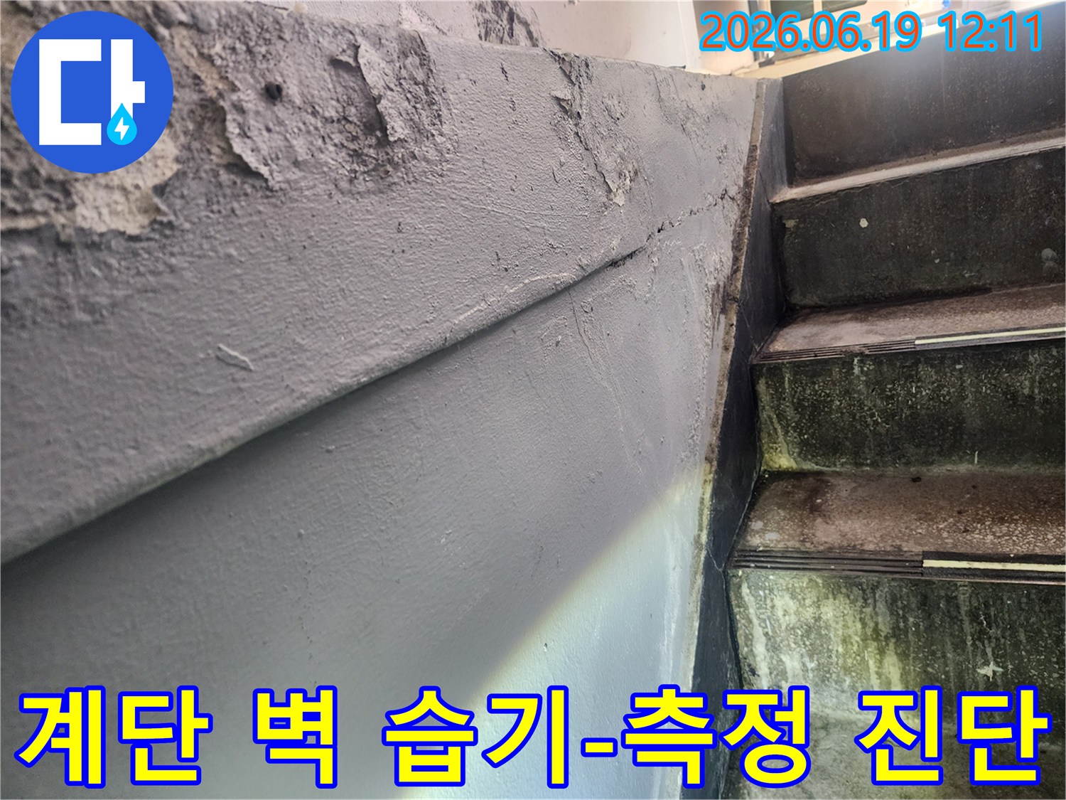 계단 옆 벽면의 페인트가 벗겨지고 습기로 인해 손상된 모습-습기 측정 및 정확한 누수 진단이 필요한 벽면 상태-건물 내부의 쾌적한 환경 유지를 위한 습기 관리