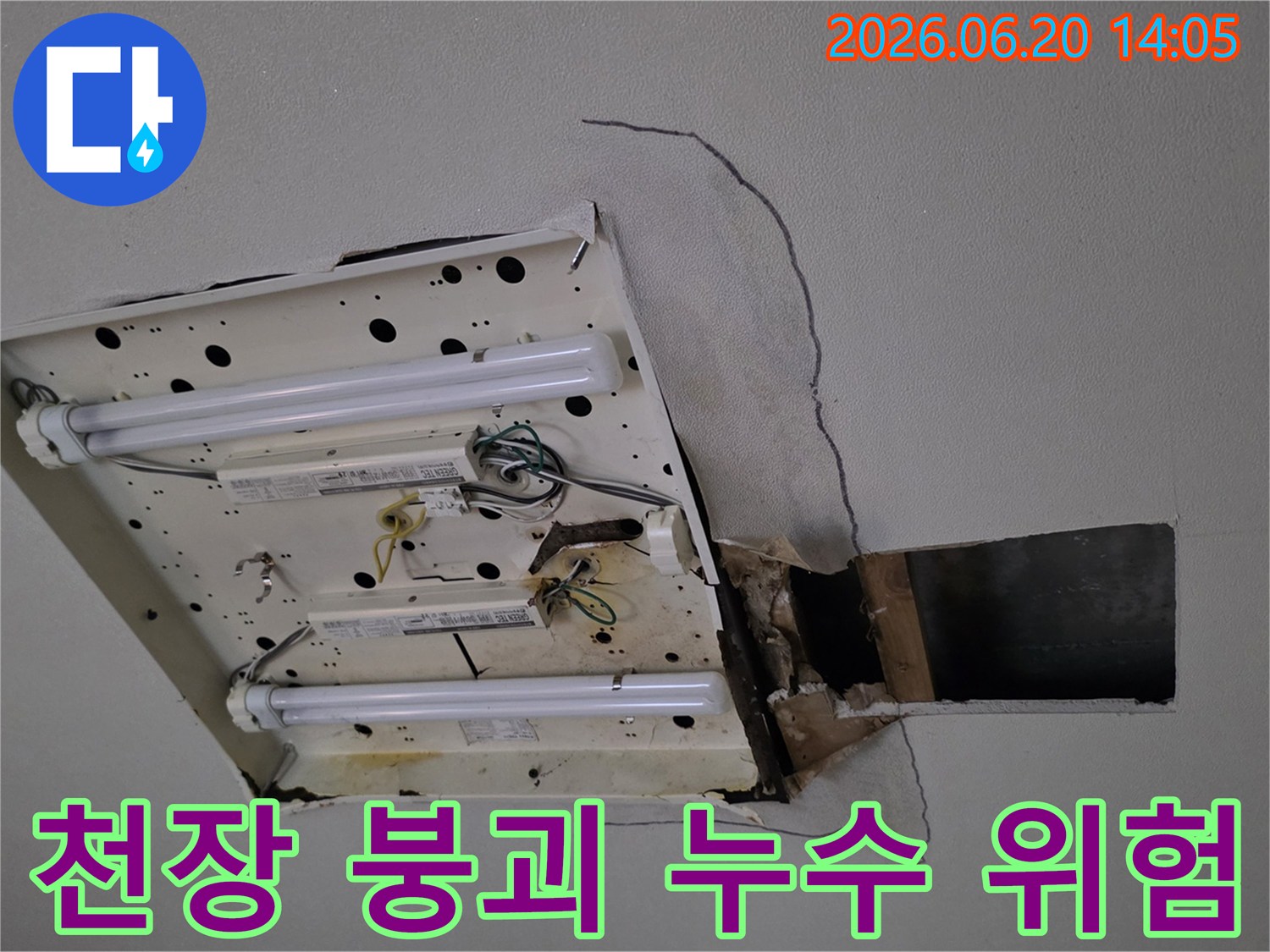 천장-형광등-주변에서-발생한-누수로-인해-석고보드가-심하게-손상되어-내부-구조물이-노출된-위험한-상황을-보여줍니다