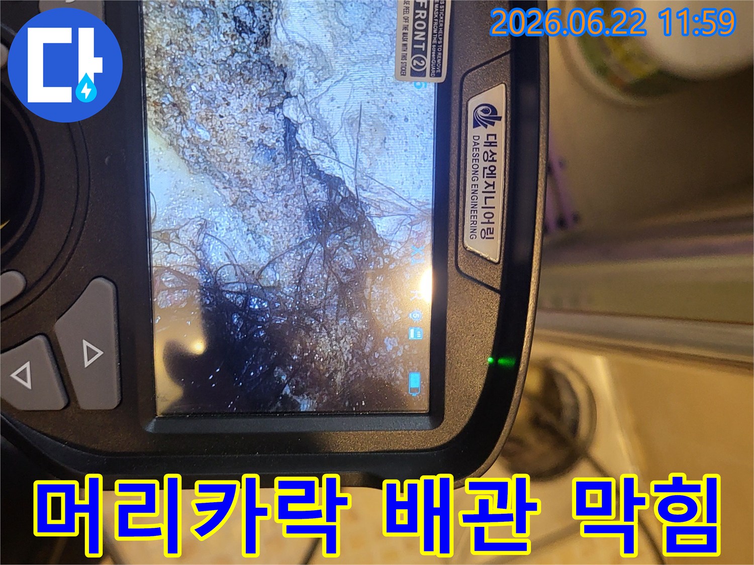 누수 탐지 전문가가-배관 내시경으로 오수관 내부를 촬영하여-머리카락과 슬러지로 막힌 상태를 확인하는 모습