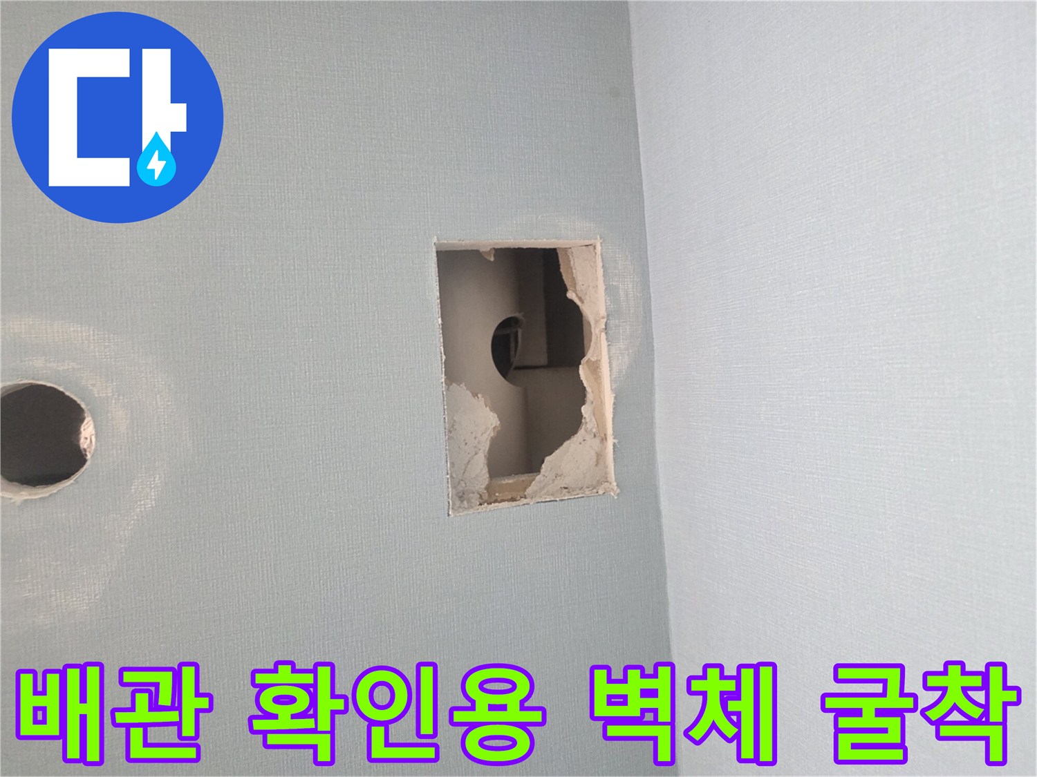 벽면의 사각형 절개 부위를 통해 - 내부 배관 상태를 면밀히 관찰합니다.