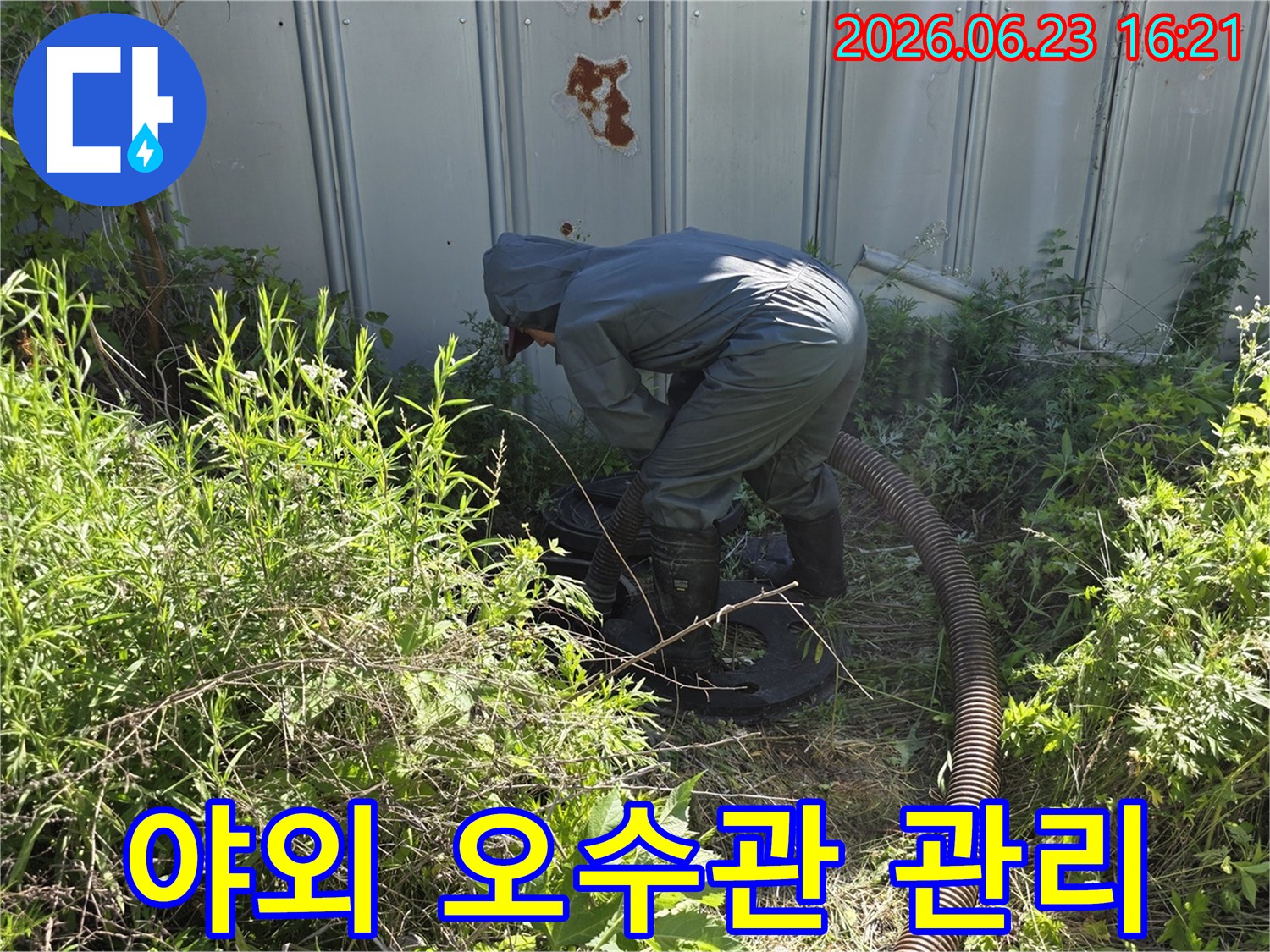 전문 작업자가 보호복을 입고 야외 오수관을 정기적으로 관리하고 청소하기 위해 흡입 작업을 하는 모습