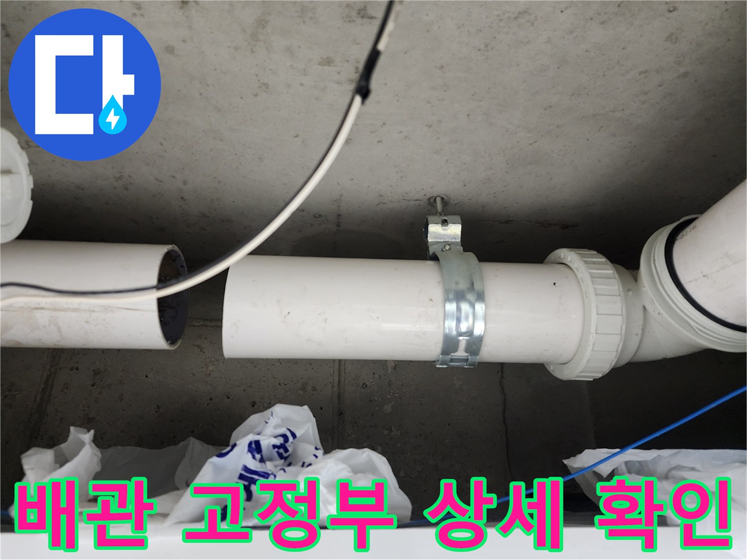 천장 내부의 흰색 배관과 금속 클램프 및 주변 전선