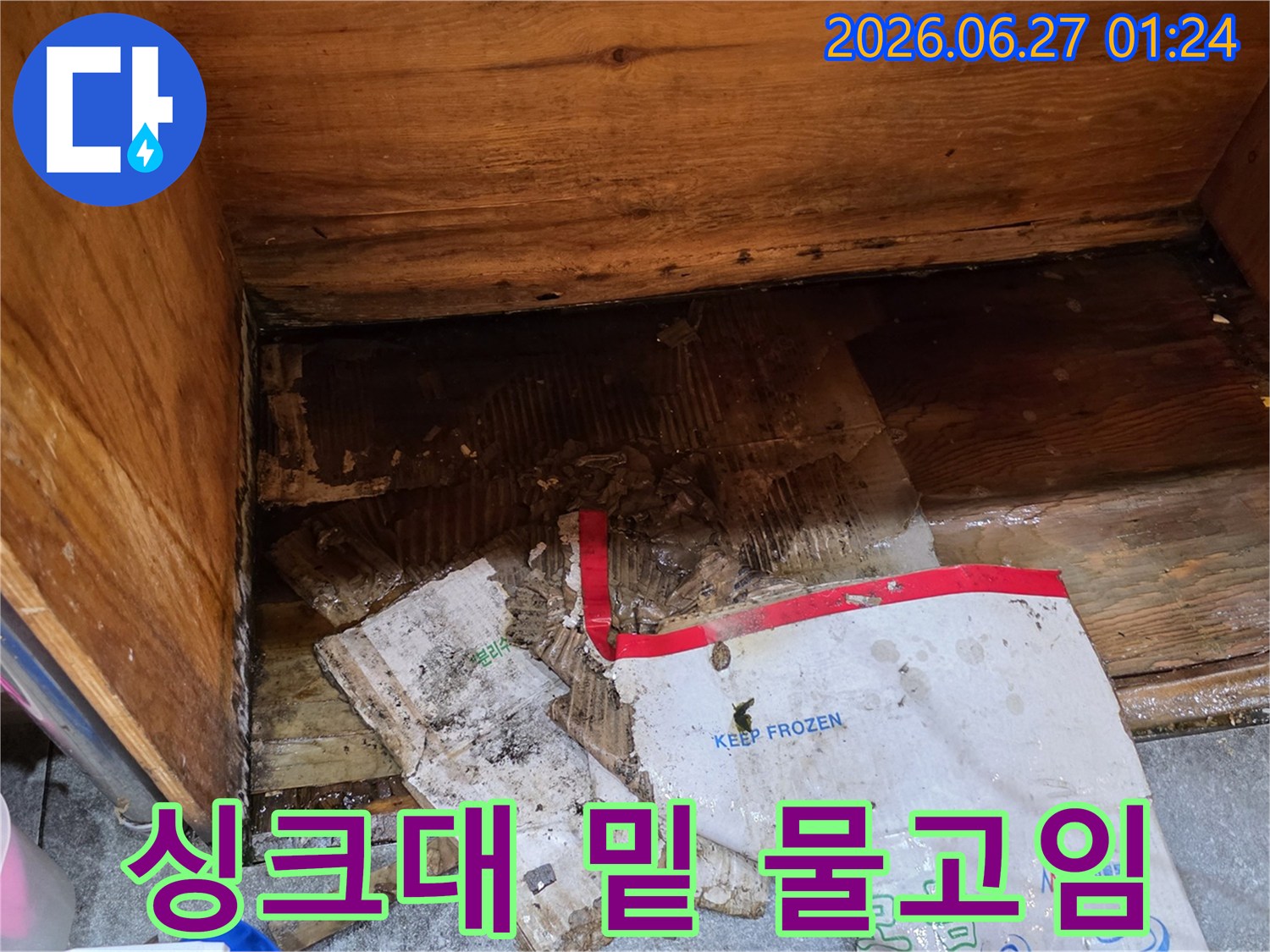 물에 젖어-파손된 종이 박스와-습기로 가득 찬-싱크대 하부의-누수 현장입니다.