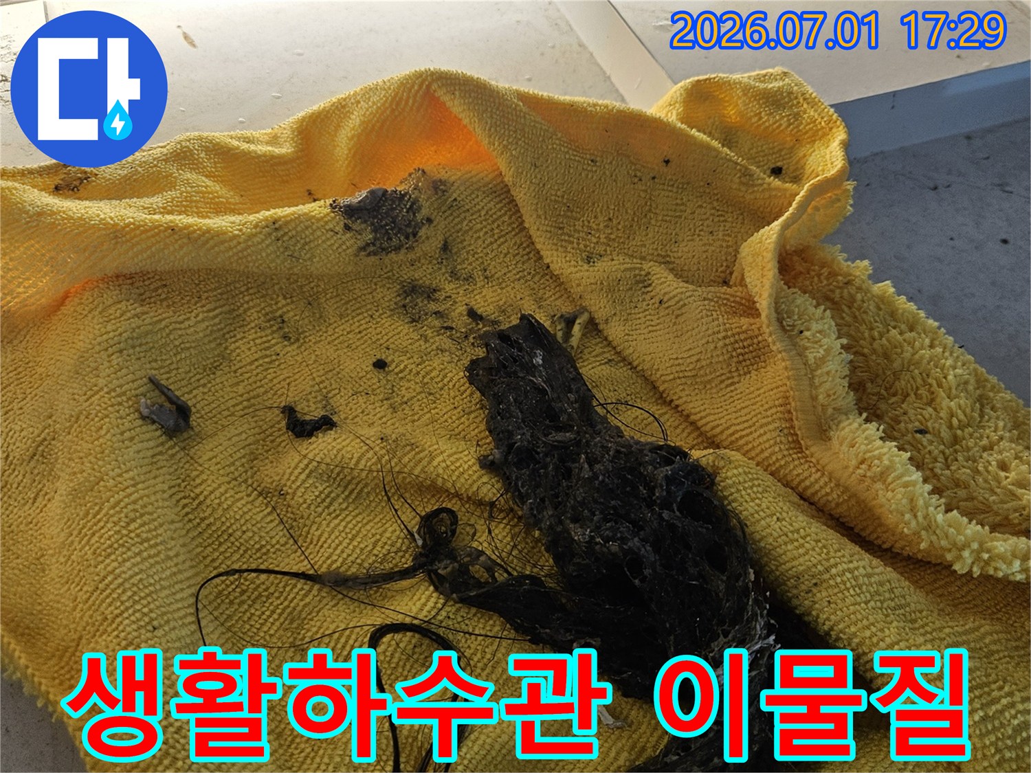 노란색 수건 위에 놓인-생활하수관에서 제거된-머리카락과 슬러지 덩어리입니다-이는 생활하수관 막힘의 주된 원인입니다