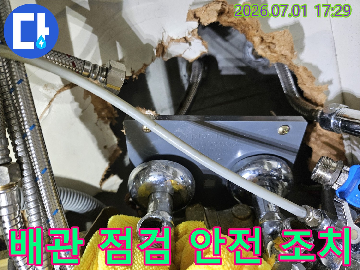 벽 안쪽의-수도 배관 연결부에서-누수 여부를-점검하고-안전 조치를-취하는 모습