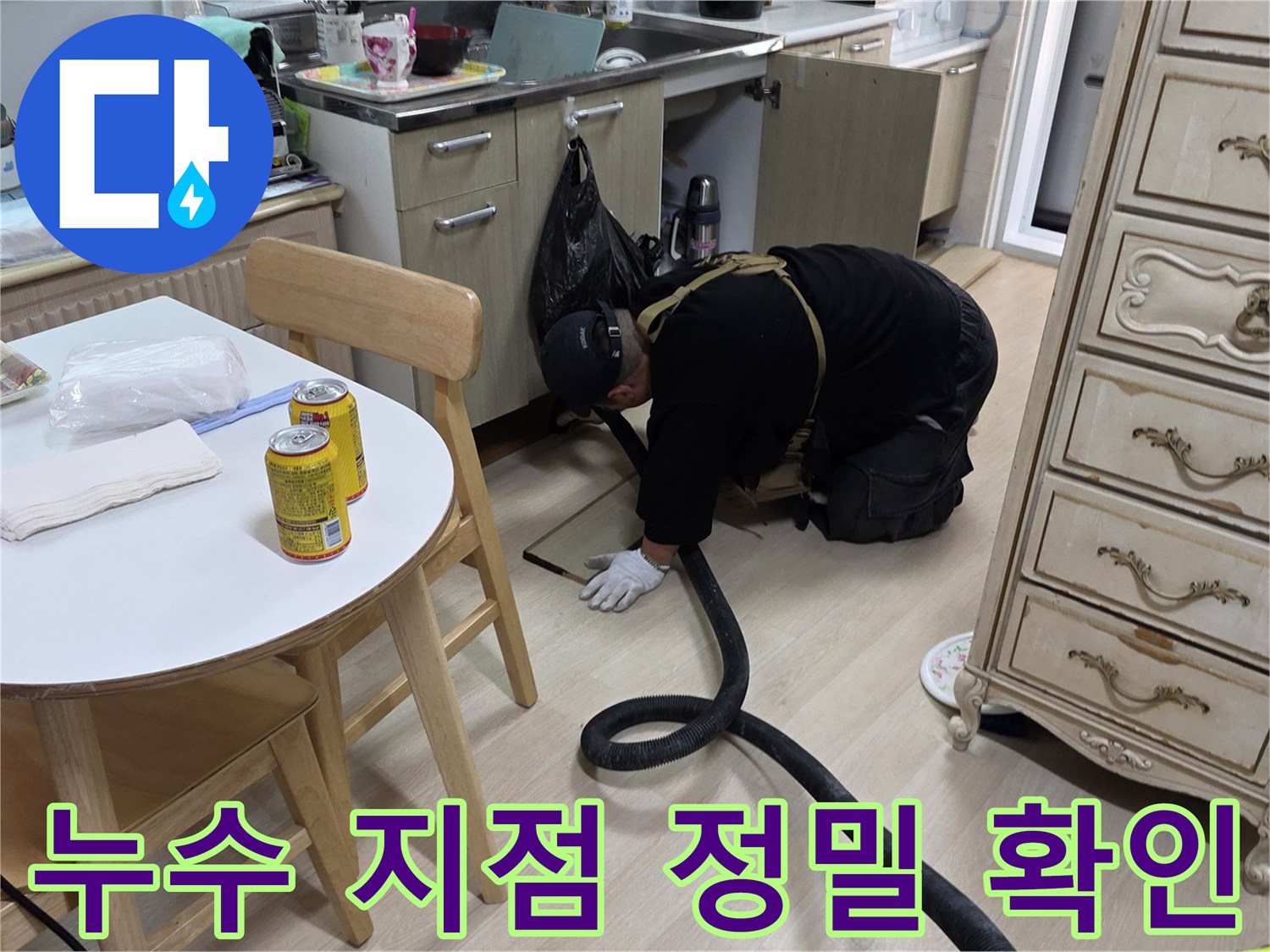 싱크대 하단 배수 호스 연결 부위를 면밀히 관찰하는 작업자