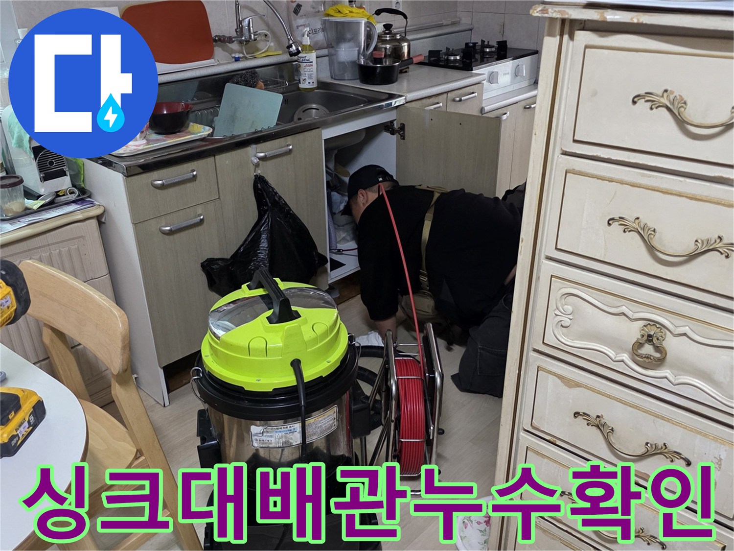작업자가 싱크대 하부의 배관 연결 상태를 꼼꼼하게 살피는 모습