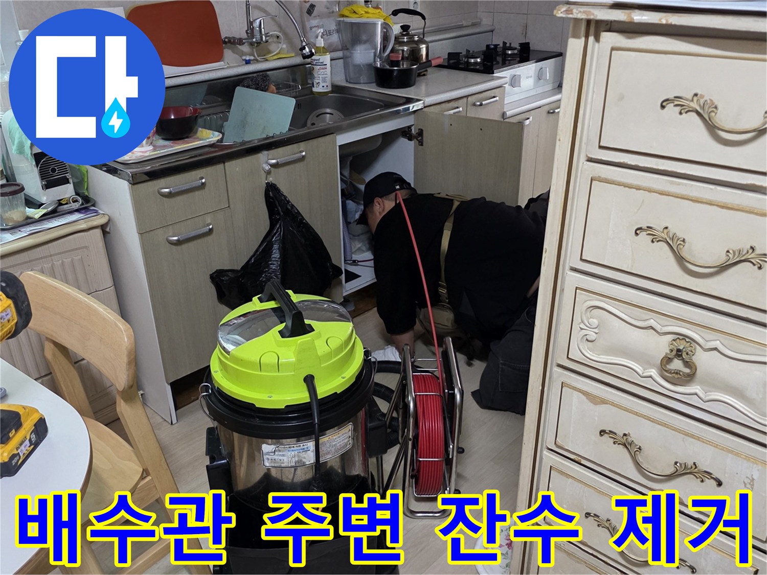 집진기를 사용하여 싱크대 하단 배관 주변의 오염된 물을 흡입하는 작업
