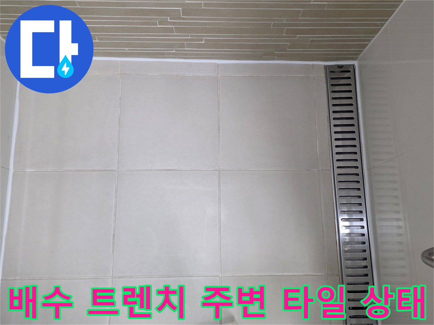 스테인리스 배수 트렌치와 인접한 화장실 바닥 타일의 모습