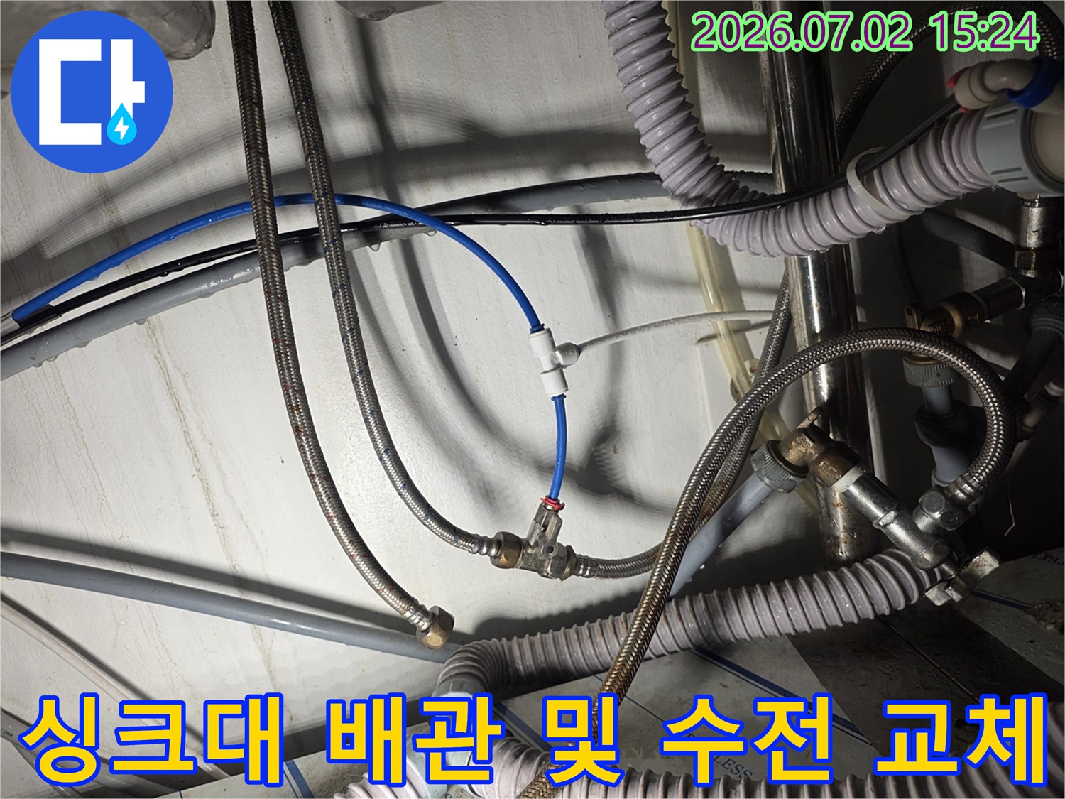 노후된 금속망 호스와 고압 호스가 복잡하게 얽힌 싱크대 하부 모습