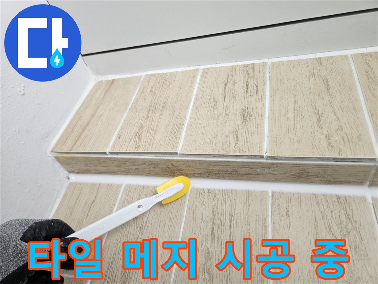 타일 틈새에 흰색 줄눈재를 채우고 있는 엔지니어의 손길