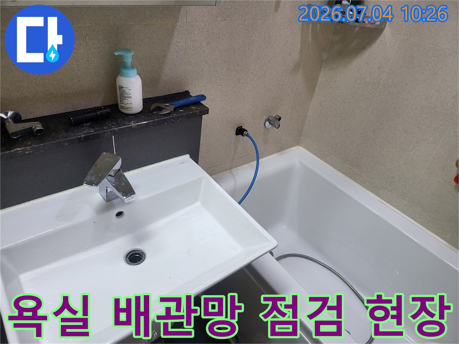 세면대 옆 파란색 호스가 연결된 구간의 배관 상태를 세밀하게 검사하는 장면