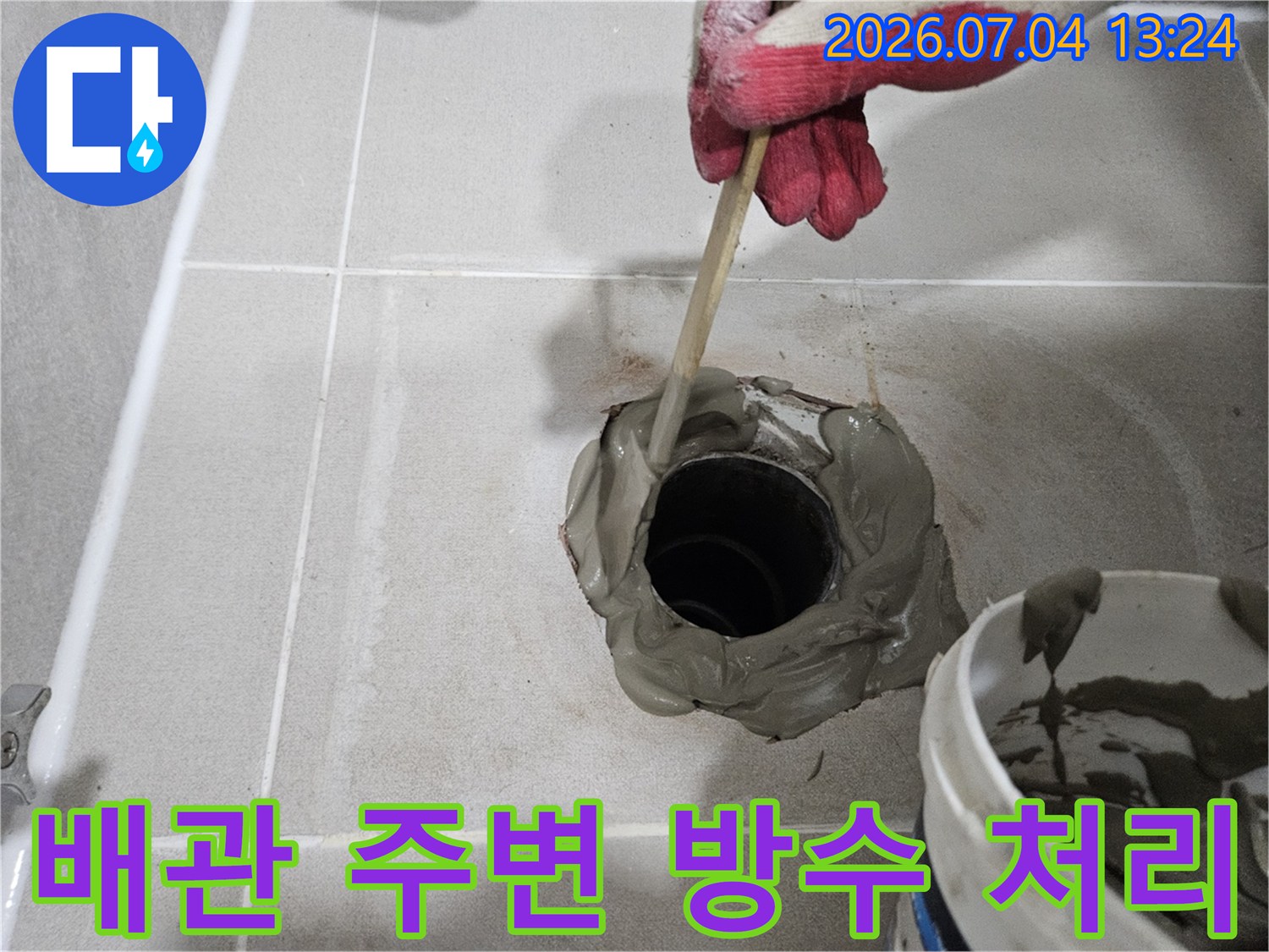고무 장갑을 착용하고 배관 주위에 충진재를 도포하는 장면