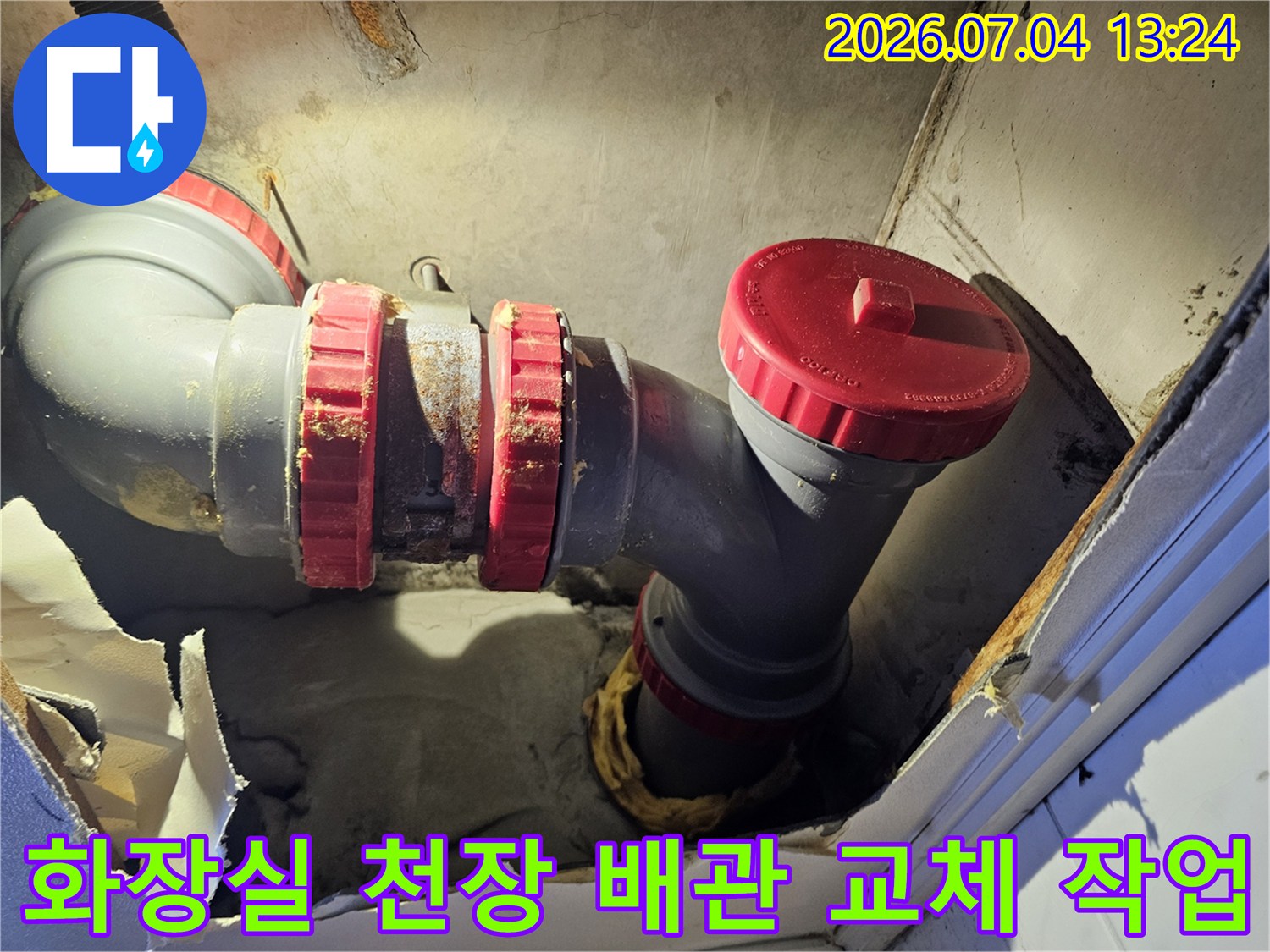 화장실 천장 내부의 노출된 배관 부위와 빨간색 캡이 씌워진 분기점 점검 모습