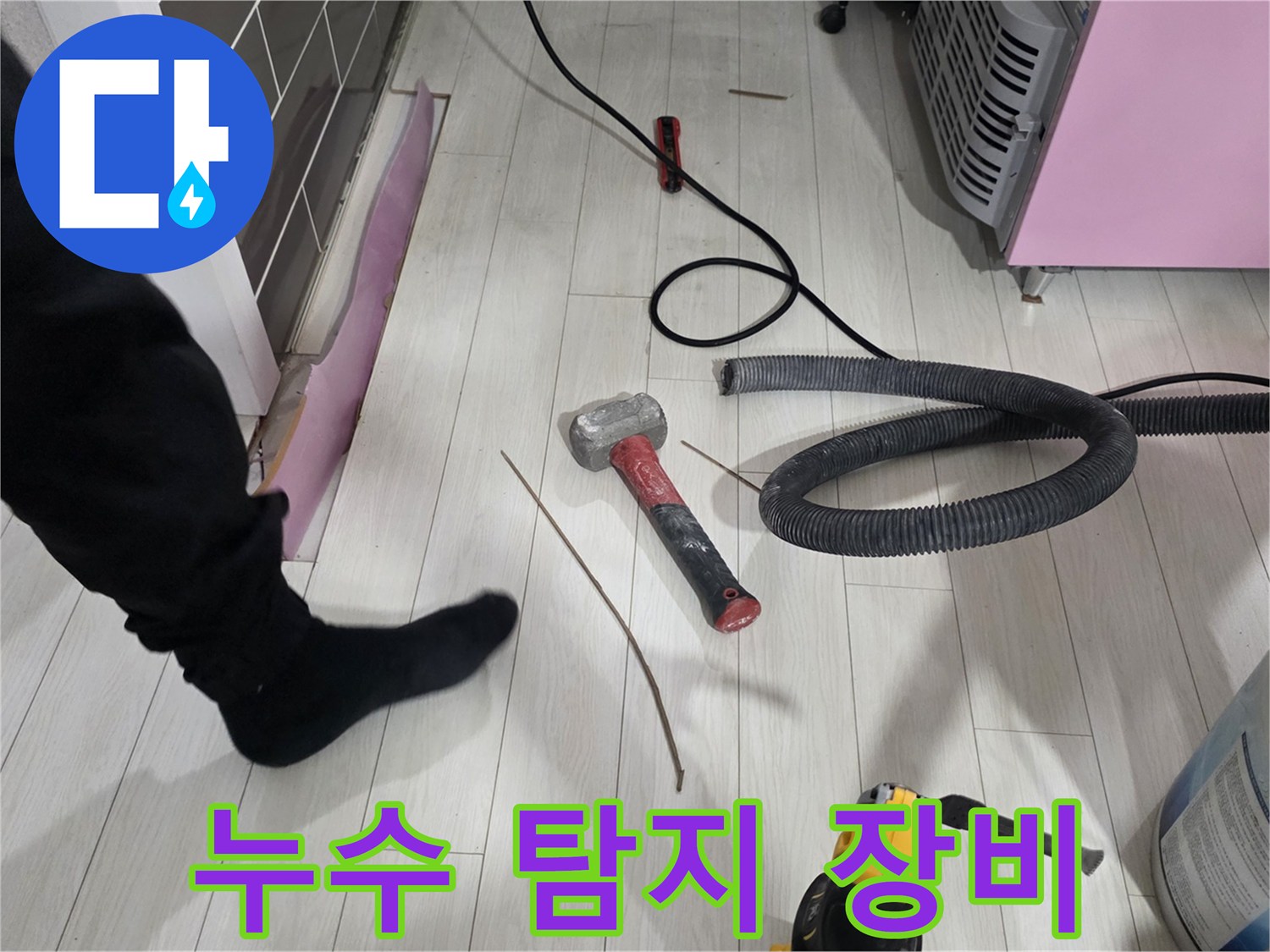 강마루 바닥에 놓인 공사 도구와 흡입용 호스 - 누수 진단 작업 중