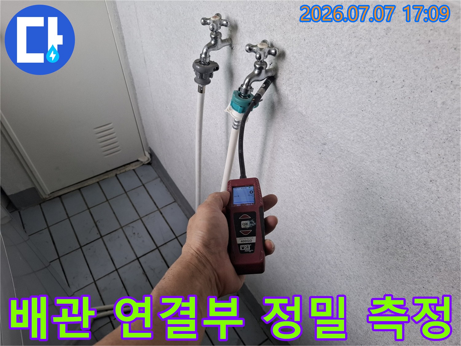 베란다 배관을 장비에 연결하여 수치로 누수 여부를 판단하는 작업 현장
