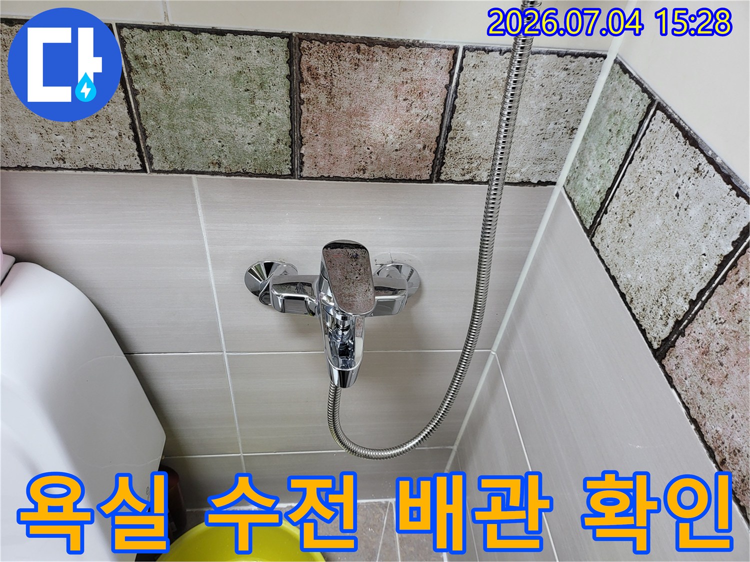 화장실 벽면 타일과 샤워기 호스가 연결된 배관 구간 촬영