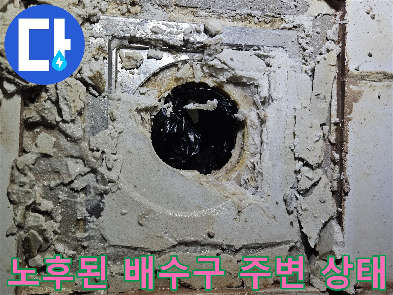 배수관 주위의 훼손된 타일과 시멘트 조각들