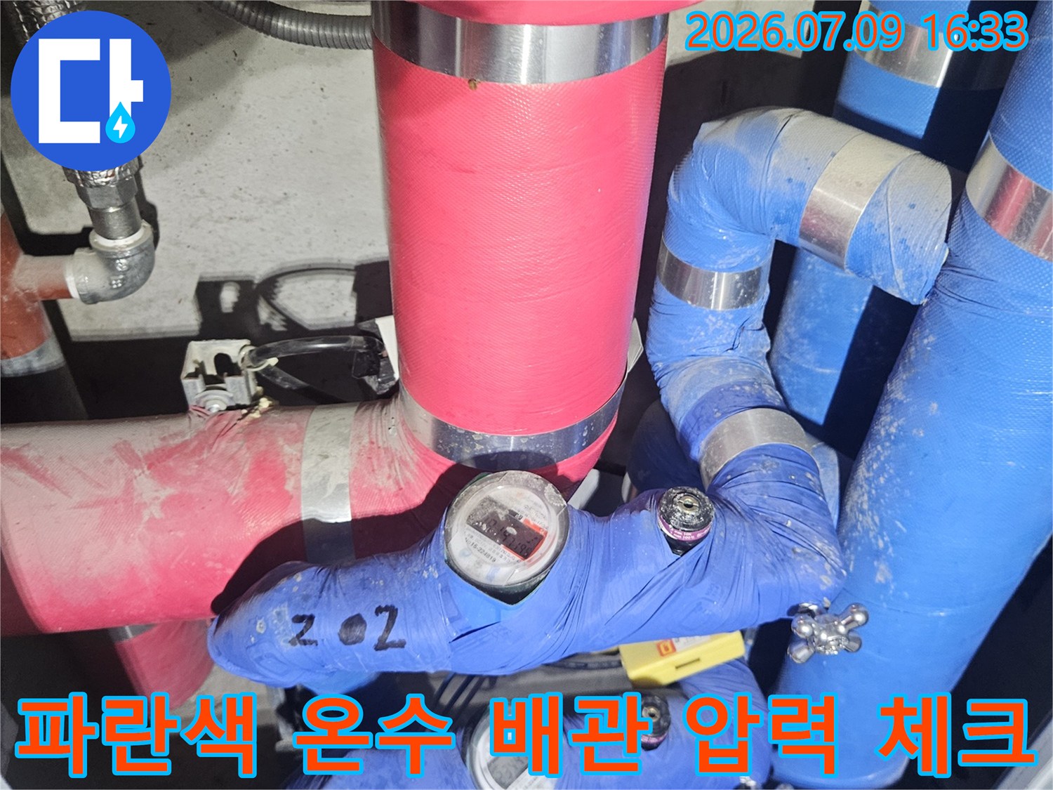 보일러실 내 설치된 압력 게이지와 파란색 보온재가 씌어진 배관들