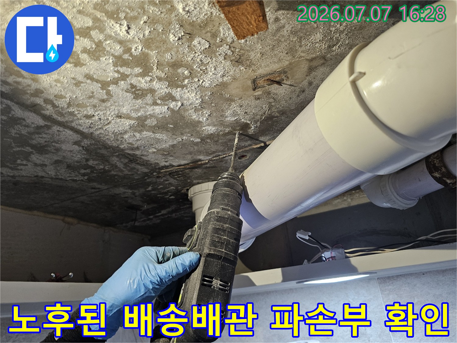 천장 안쪽의 노후된 백색 배출 배관 연결 부위를 세밀하게 검사하는 모습