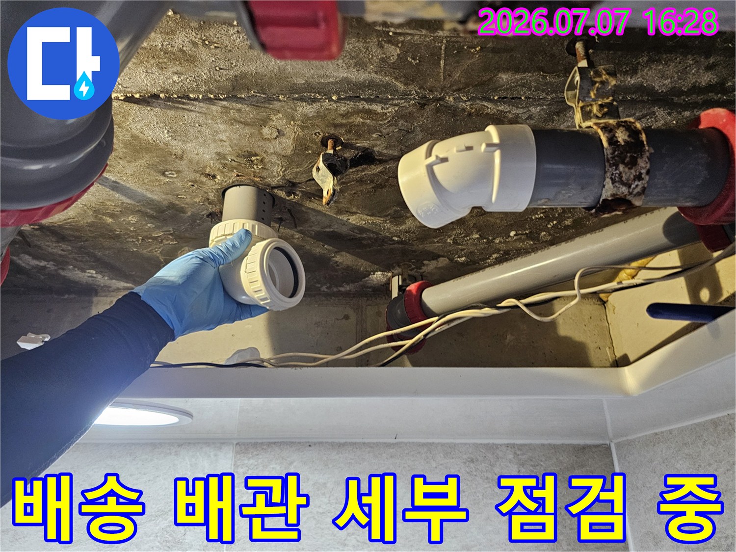 한 손에 쥔 새 부품과 기존의 노후된 파이프를 비교하며 확인하는 모습