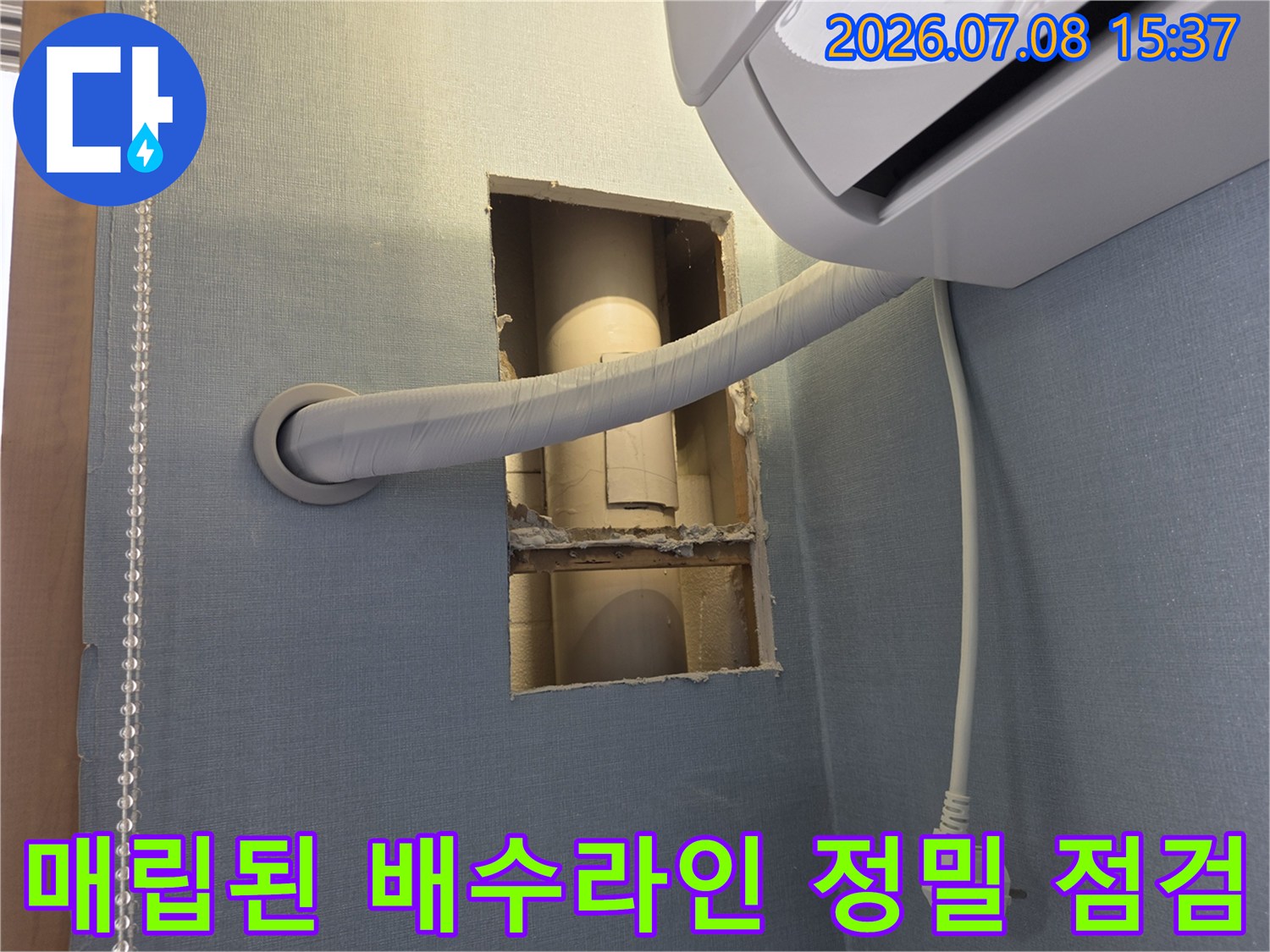 벽면을 절개하여 노출시킨 에어컨 드레인 호스의 상태를 파악하는 현장 사진