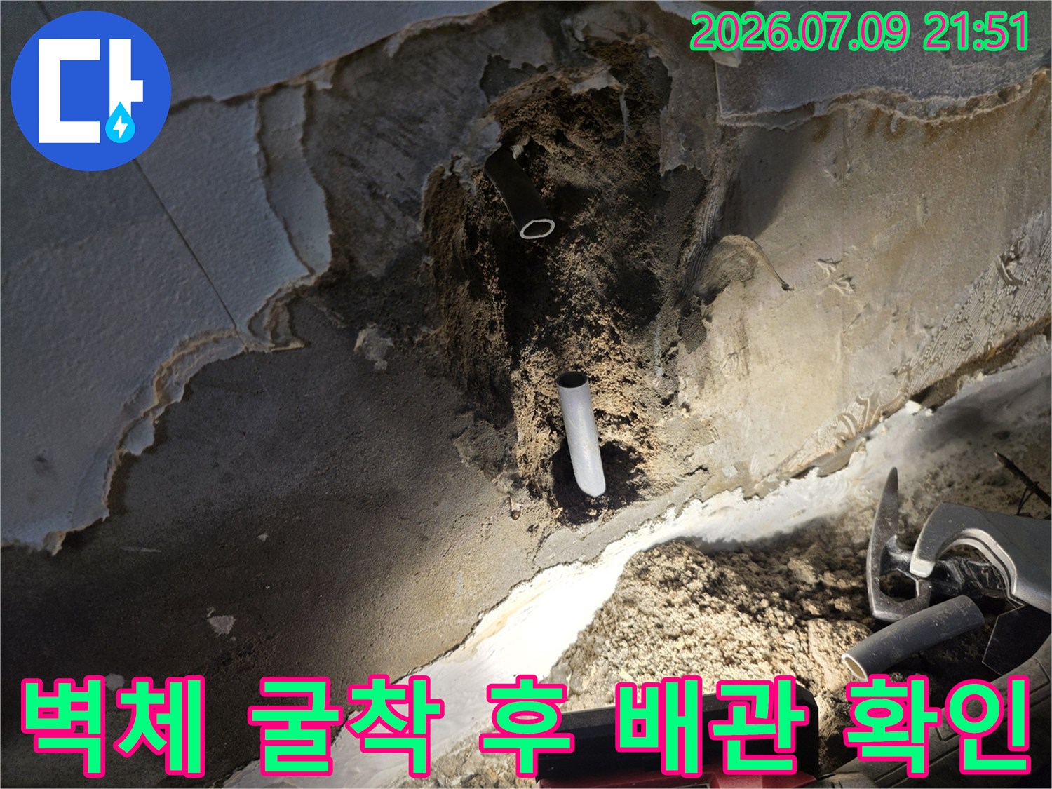 노출된 하얀색 배관과 거칠게 파헤쳐진 벽면의 내부 모습
