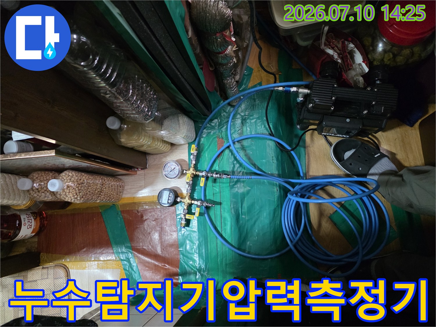 파란색 호스와 압력 게이지가 연결된 누수 탐지 장비와 배관 점검 현장