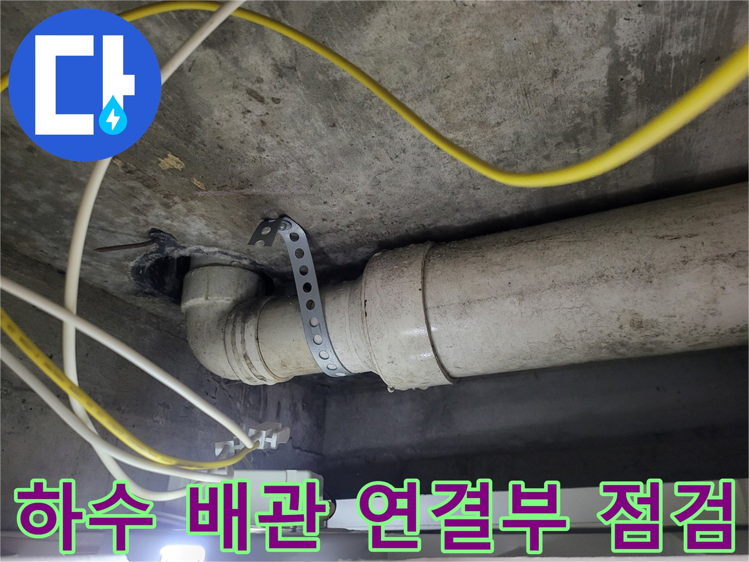 천장 아래로 노출된 하수관과 고정용 클램프의 근접 사진입니다.