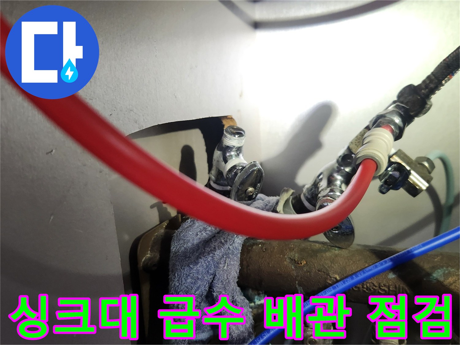싱크대 하부의 붉은색 호스와 은색 밸브 연결 부위 상세 사진