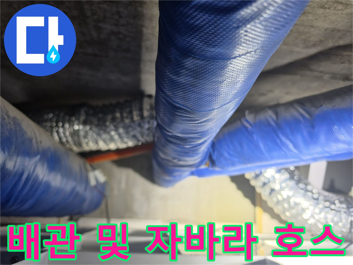 천장에 설치된 파란색 보온재 배관과 은색 자바라 호스의 근접 촬영