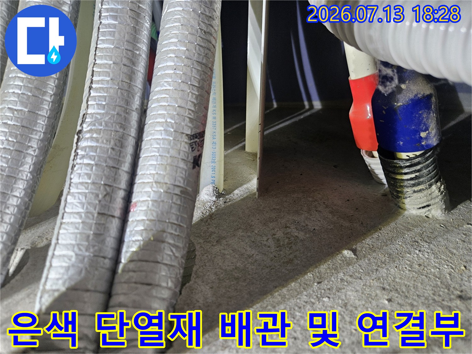 배관 보호를 위해 설치된 은색 마감재와 수도 연결용 파란색 부품